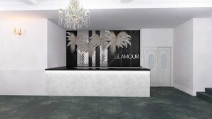 A reception area with a marble counter, a chandelier, and a wall with palm trees and the word "GLAMOUR". - AQUAREL health & spa center (Zalau)