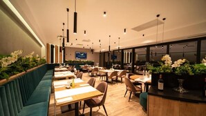 A modern restaurant with wooden tables, teal cushioned seating, and hanging pendant lights. - AQUAREL health & spa center (Zalau)