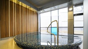 A circular hot tub with a mosaic tile interior, a metal ladder, and a wooden panel wall with vertical slats. - AQUAREL health & spa center (Zalau)