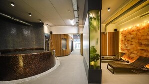 A spa area with a hot tub, lounge chairs, and a wall with a textured pattern. - AQUAREL health & spa center (Zalau)