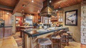 Una cocina amplia con armarios de madera, una isla grande con taburetes de bar y una pared decorativa de piedra.