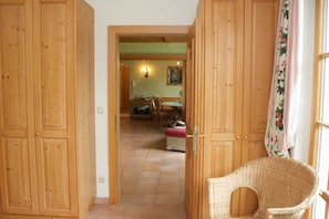 A wooden interior with a dining area, a wicker chair, and a door leading to another room.