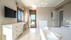 Ein Schlafzimmer mit Bett, Fernseher, Kommode, Stuhl und Meerblick.