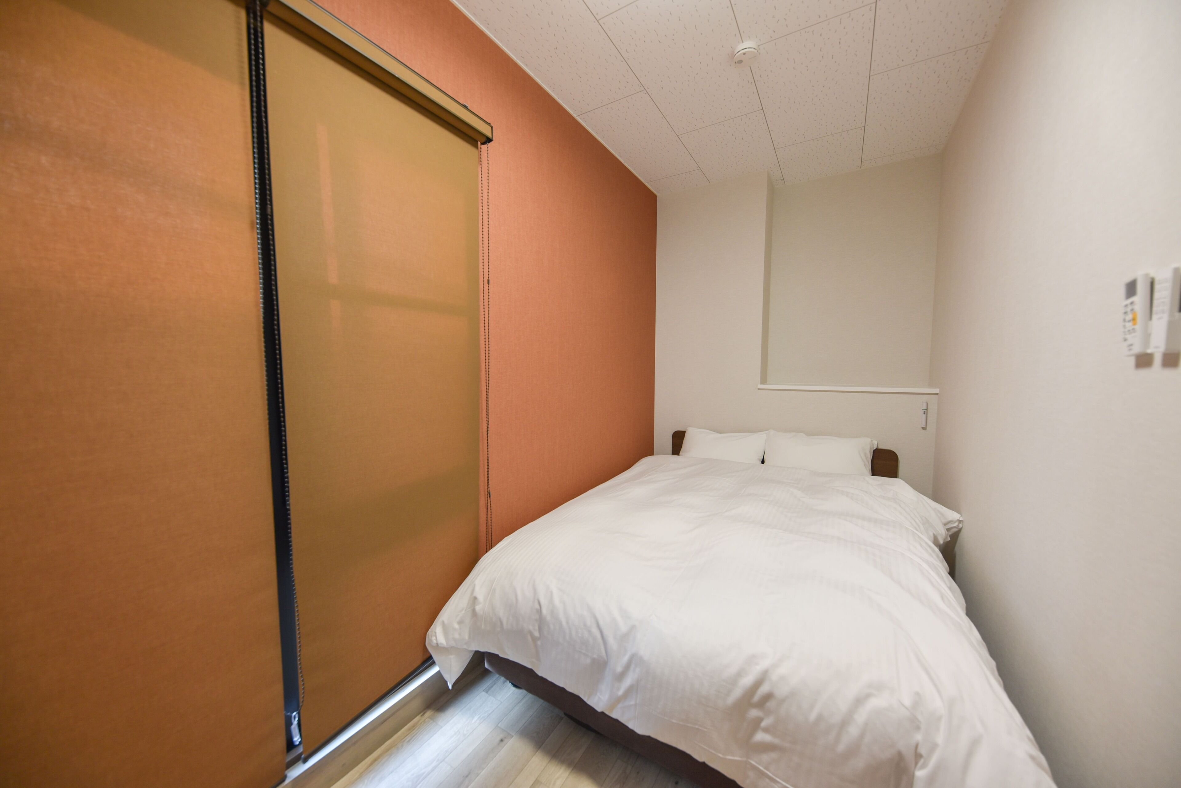 A bedroom with a bed, a sliding door, and a white wall with a mirror.