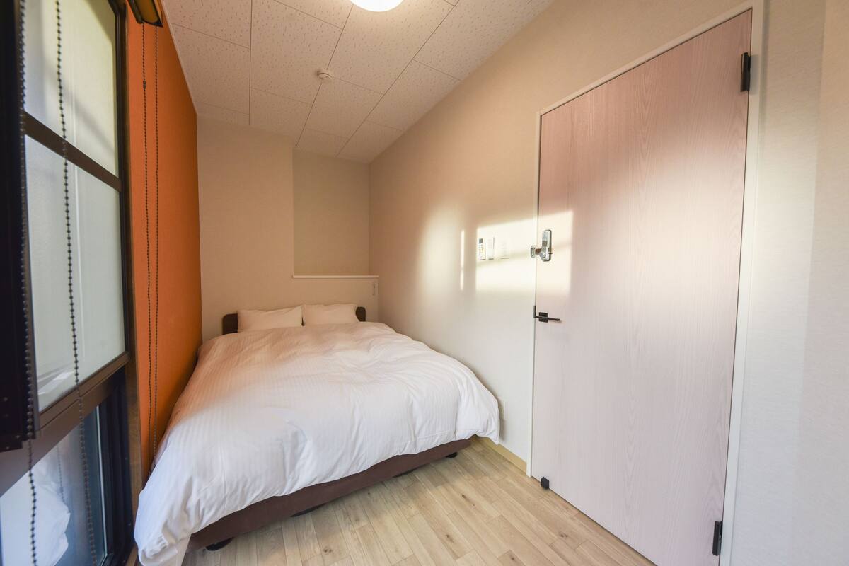 Une chambre à coucher avec un lit, une armoire et une fenêtre équipée de stores.