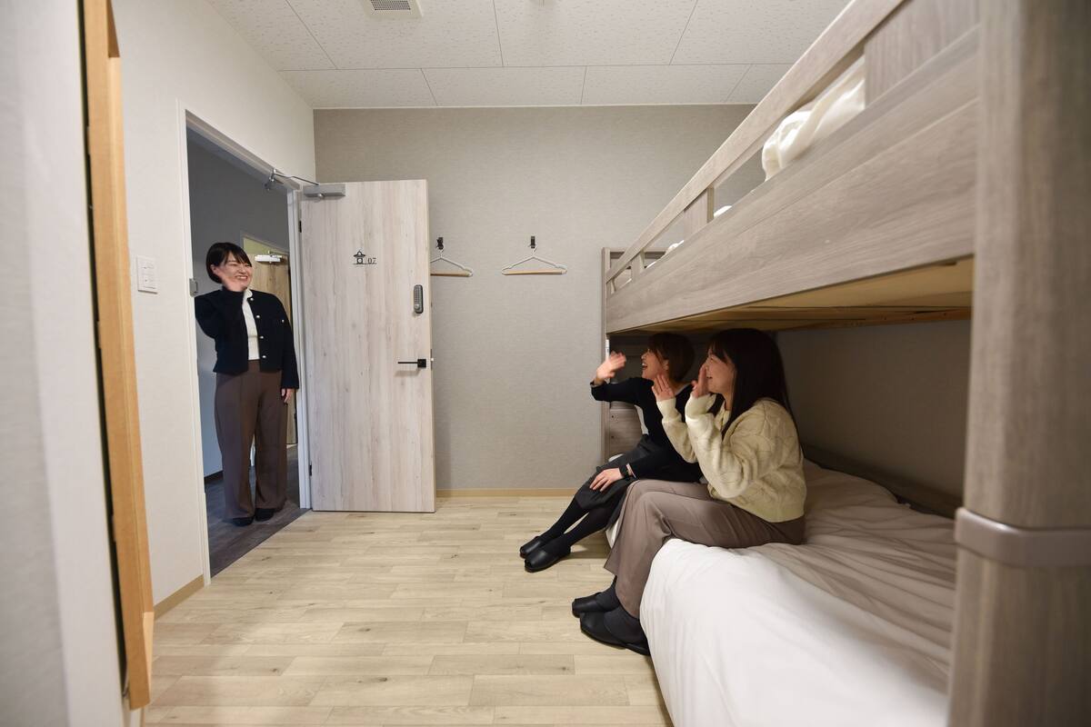 Une pièce avec un lit superposé, une porte en bois et un plancher de couleur claire.