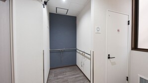 Un couloir étroit avec un plancher en bois, un mur bleu et une porte blanche dotée d’une poignée noire.