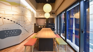 Un intérieur moderne avec une table en bois et des chaises colorées, une carte accrochée au mur et de grandes fenêtres.