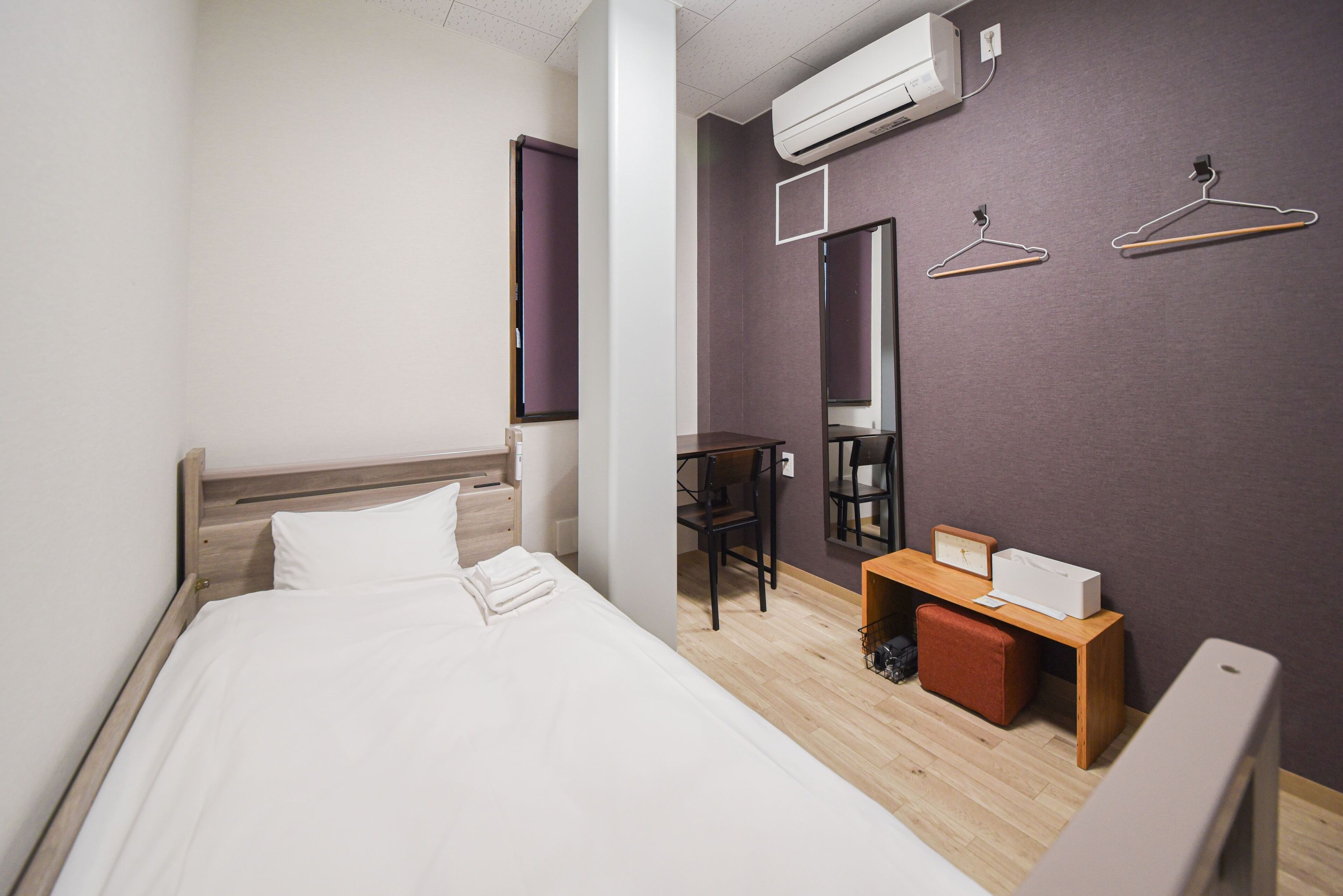 Une chambre d’hôtel moderne équipée d’un lit, d’un bureau, d’une chaise et d’une armoire.
