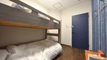 A bunk bed with a wooden frame and white bedding, a door with a blue curtain, and a wooden floor.
