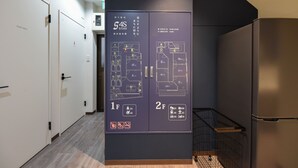 Un couloir où est affiché un plan des lieux, indiquant les numéros des pièces et les équipements disponibles.