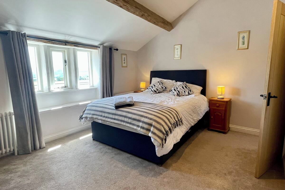 Une chambre à coucher avec un lit, des lampes de chevet, une fenêtre avec des rideaux et une porte.