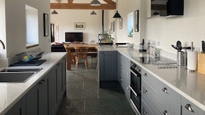 Une cuisine moderne avec des meubles gris, un grand îlot central et un plafond en pierre.