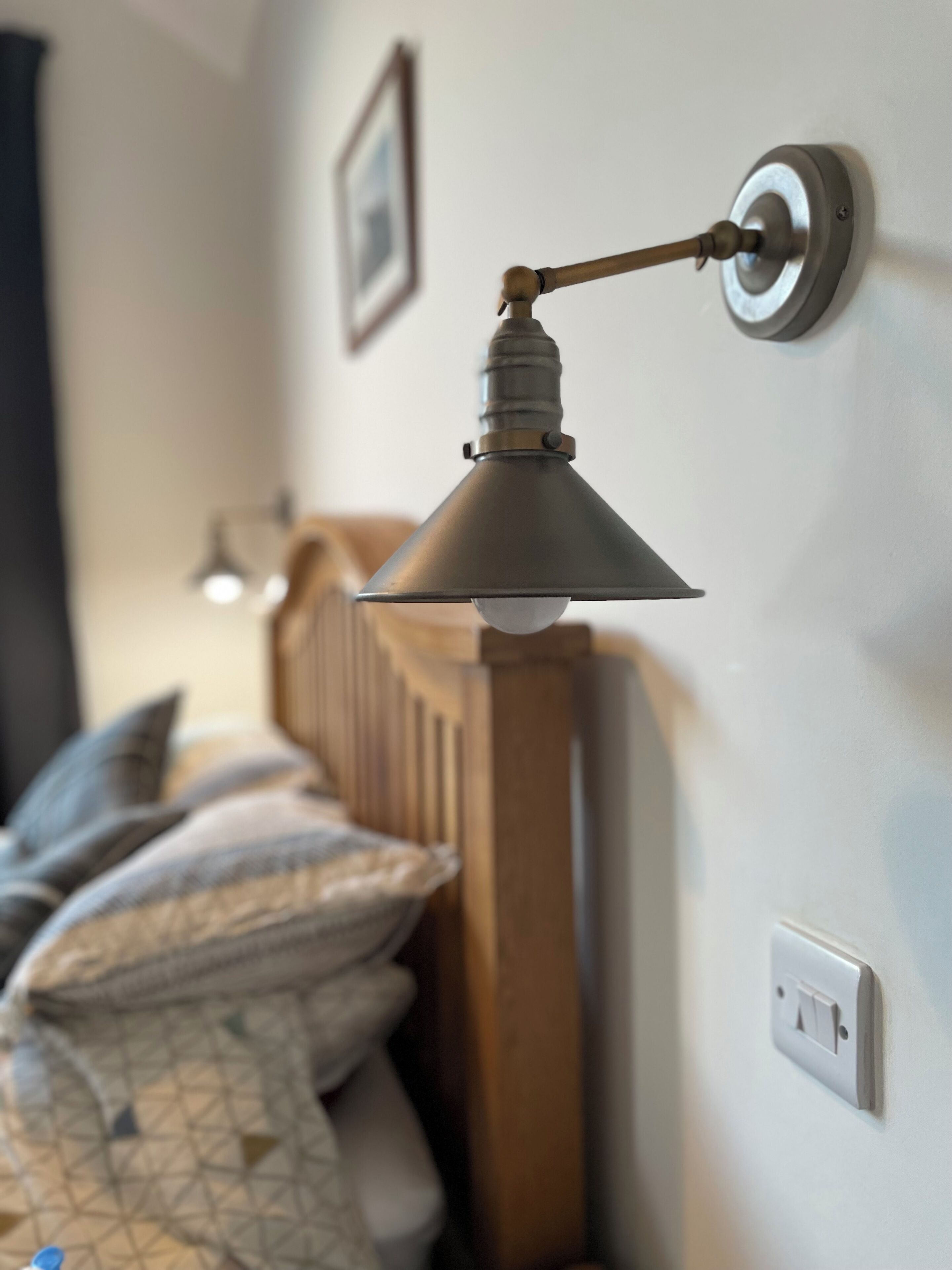 Une lampe murale dotée d’un abat-jour conique, d’un interrupteur et d’une douille pour ampoule.