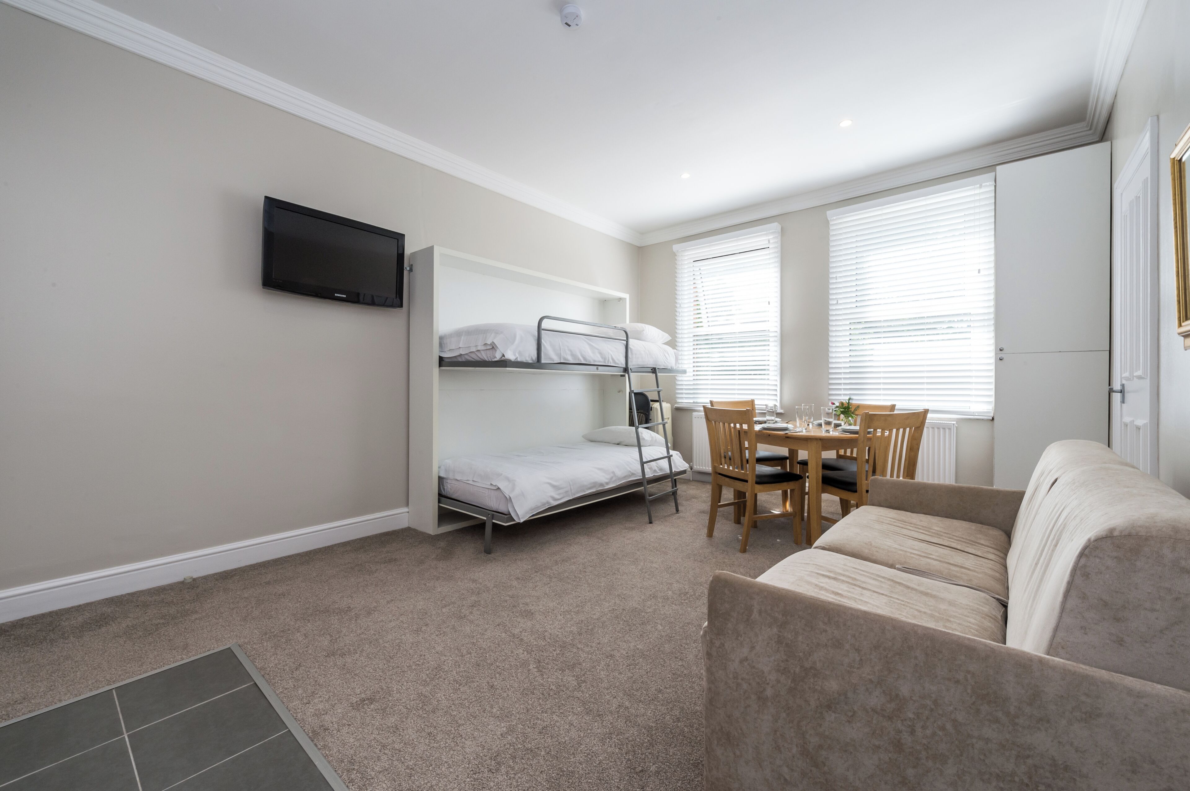 A compact room with bunk beds, a dining table, and a sofa.