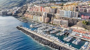 A coastal cityscape with a marina filled with boats, a rocky breakwater, and residential buildings along the hillside. - Apartment in Radazul with Stunning Sea Views (Radazul)