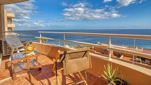 A balcony with a view of the ocean, lounge chairs, a table with fruit, and a small plant. - Apartment in Radazul with Stunning Sea Views (Radazul)