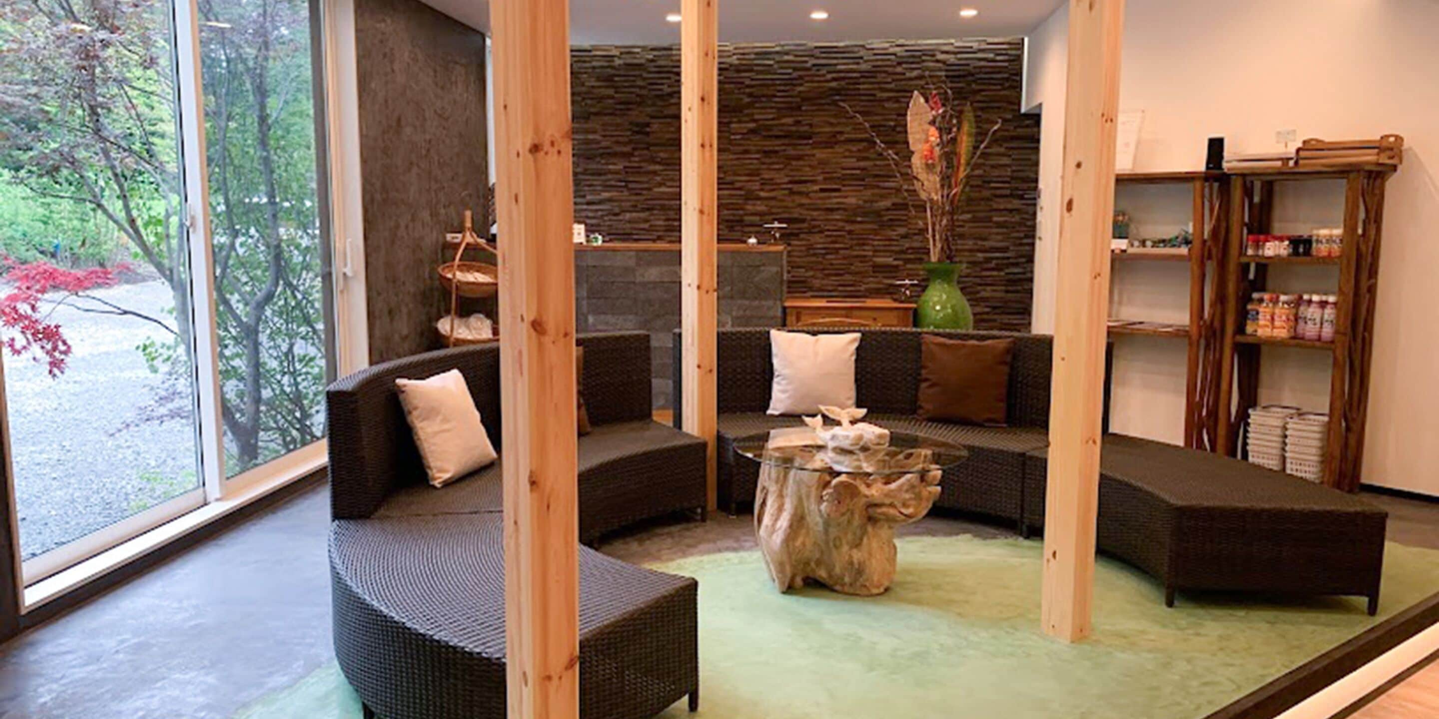 Ein modernes Interieur mit Rattan-Sofas, einem Holztisch und einer Steinwand.