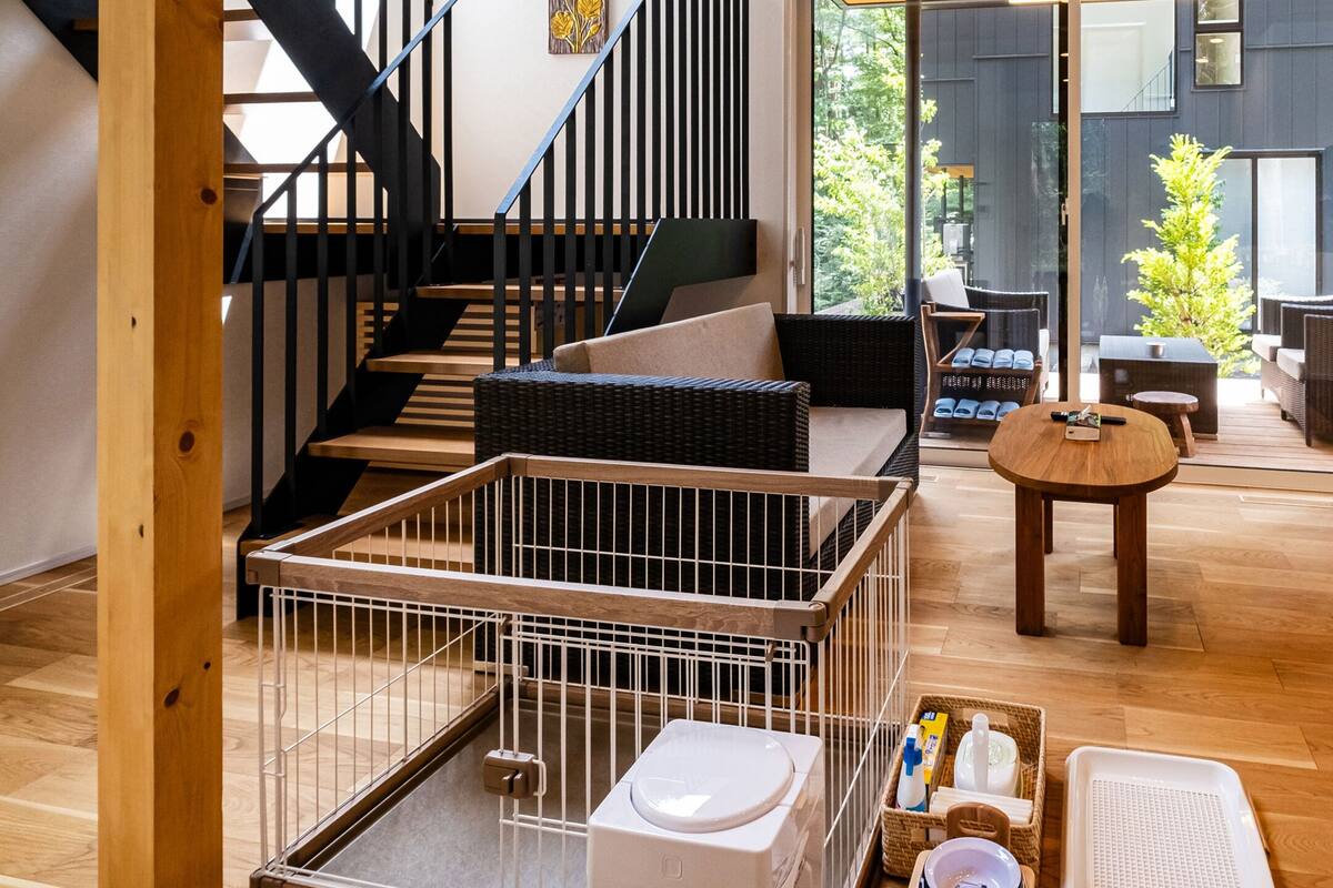 A modern interior with a wooden staircase, a balcony with wicker furniture, and a TV mounted on the wall.