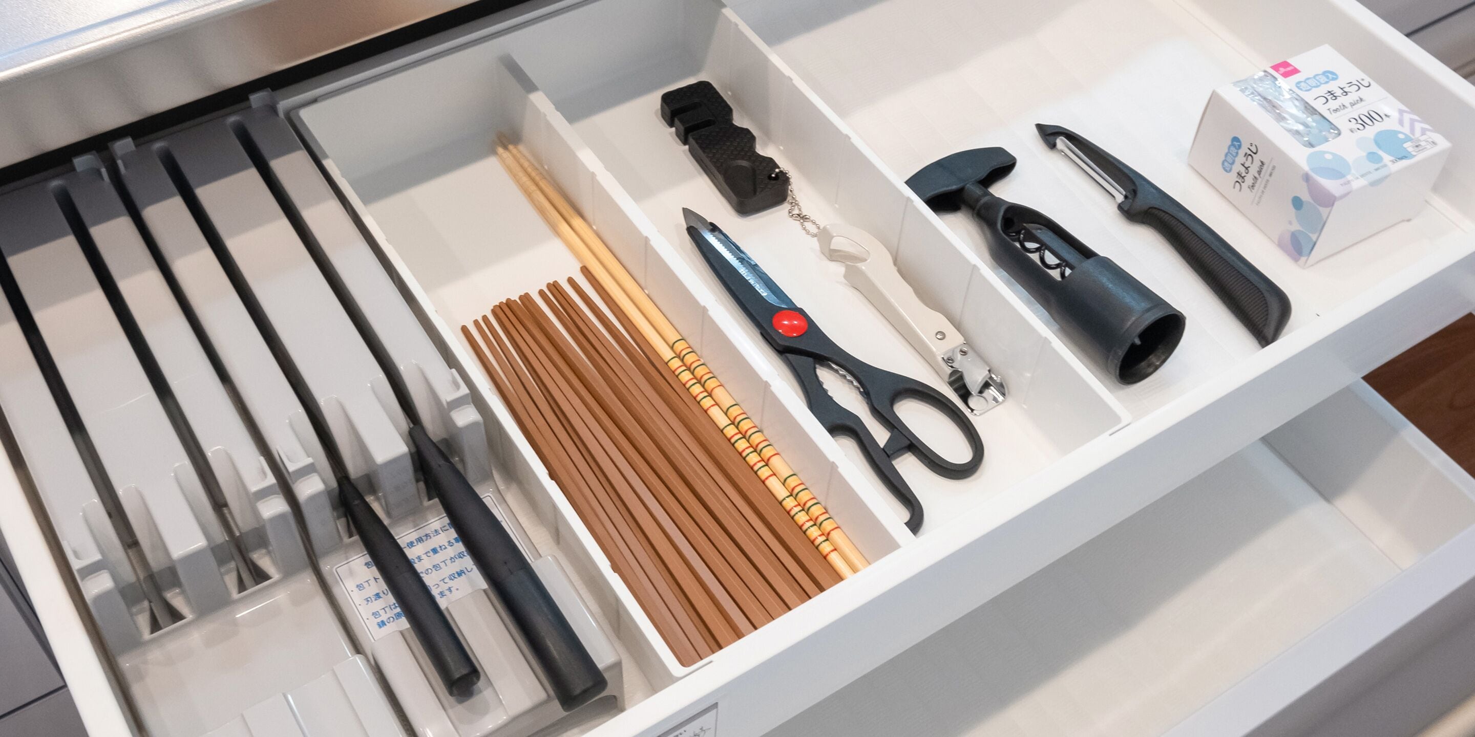 Un tiroir contenant divers articles de bureau, notamment des ciseaux, des stylos et une agrafeuse.