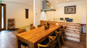 Un tavolo da pranzo in legno con sedie, un angolo cottura con elettrodomestici e un arazzo decorato.