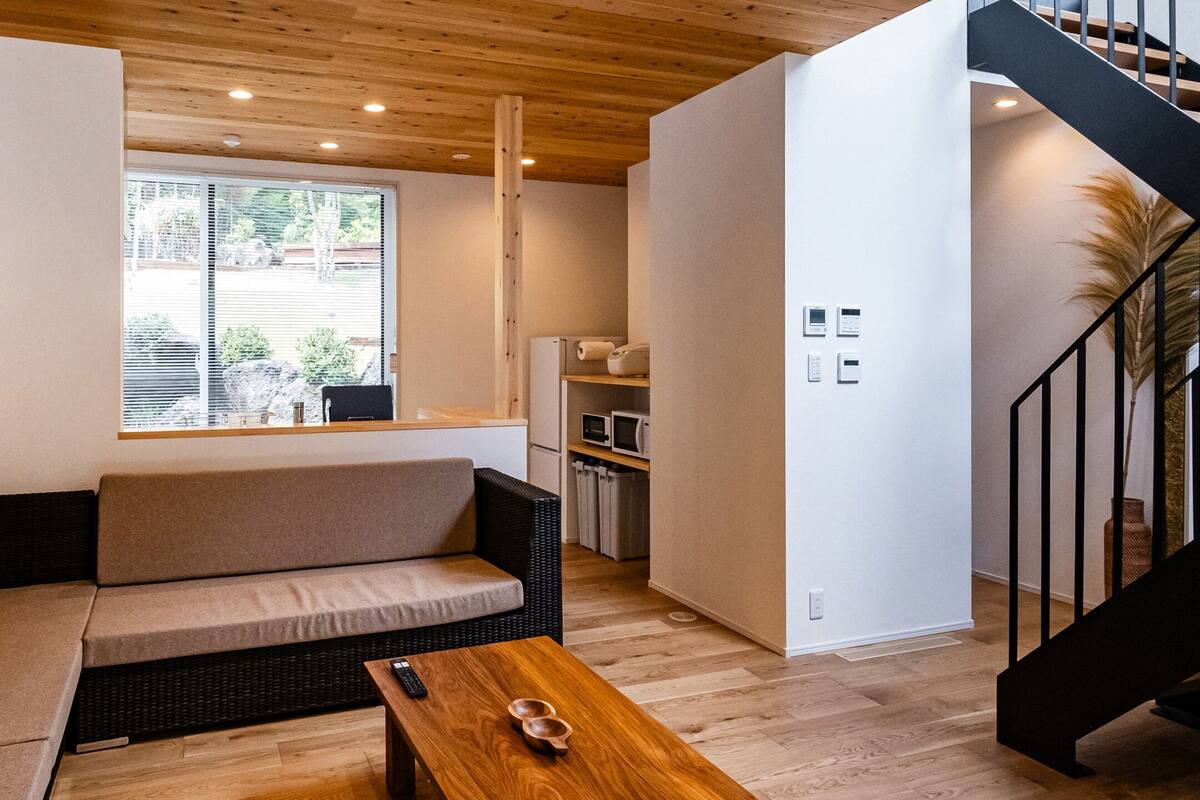 A modern living room with a sofa, a wooden coffee table, and a window with blinds.