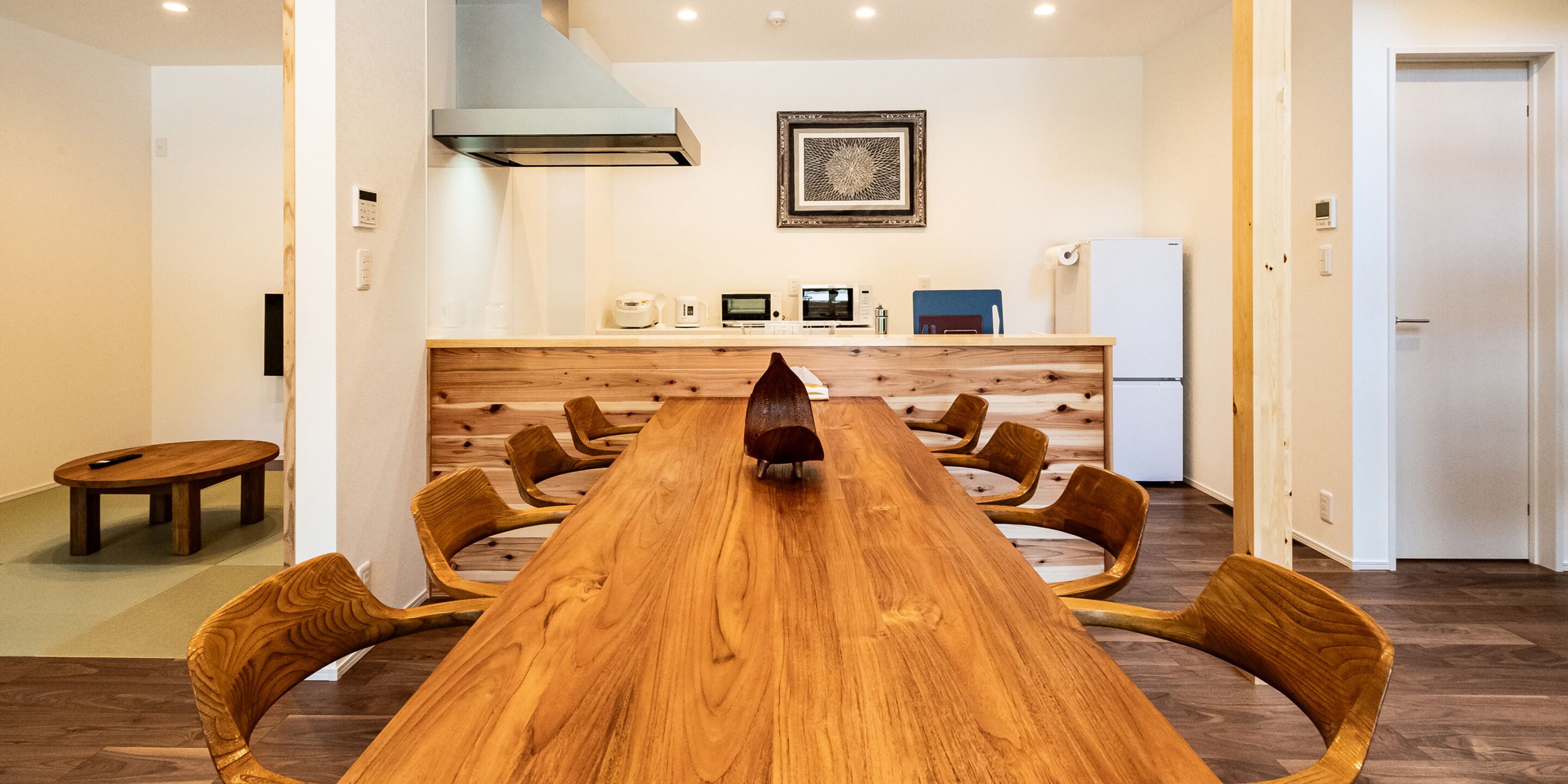 A modern kitchen with a wooden island, built-in appliances, and a framed artwork on the wall.
