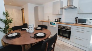 A compact kitchen with a microwave, oven, and stainless steel range hood. - Street View Modern Apartment (Hull)