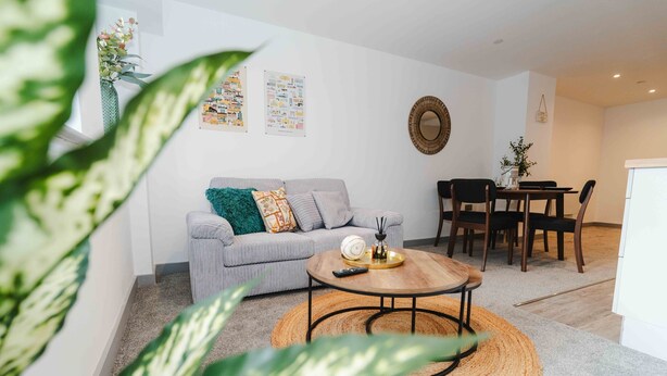 A living room with a sofa, coffee table, and dining area with chairs. - Street View Modern Apartment (Hull)