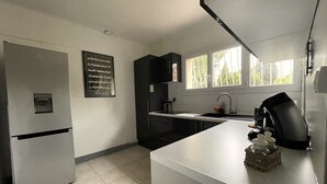 A modern kitchen with a refrigerator, black cabinets, a white countertop, and a window providing natural light.
