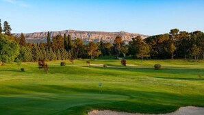 A golf course with a flagstick, sand bunkers, and trees. - LE Gîte LA Maison DE Papou Le Tilleul (Nans-les-Pins)