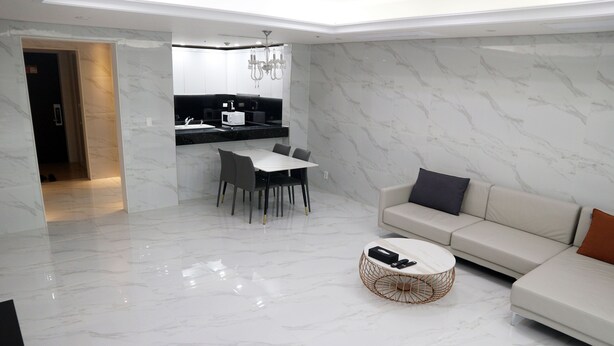 A modern living room with a white sofa, a coffee table, and a dining area with a table and chairs. - W Residence Hotel Centum City (Busan)