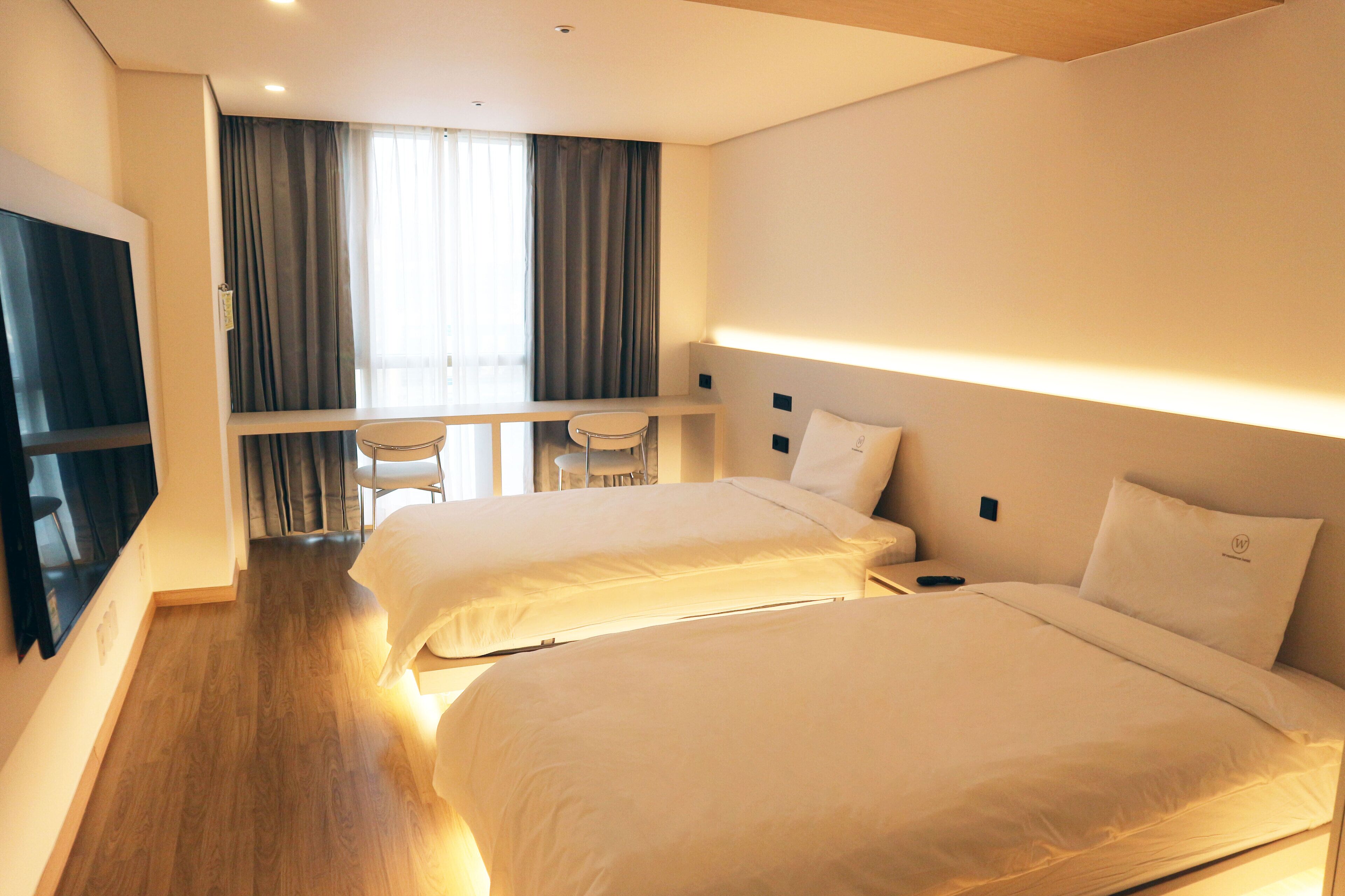 Een hotelkamer met twee bedden, een bureau en een televisie.