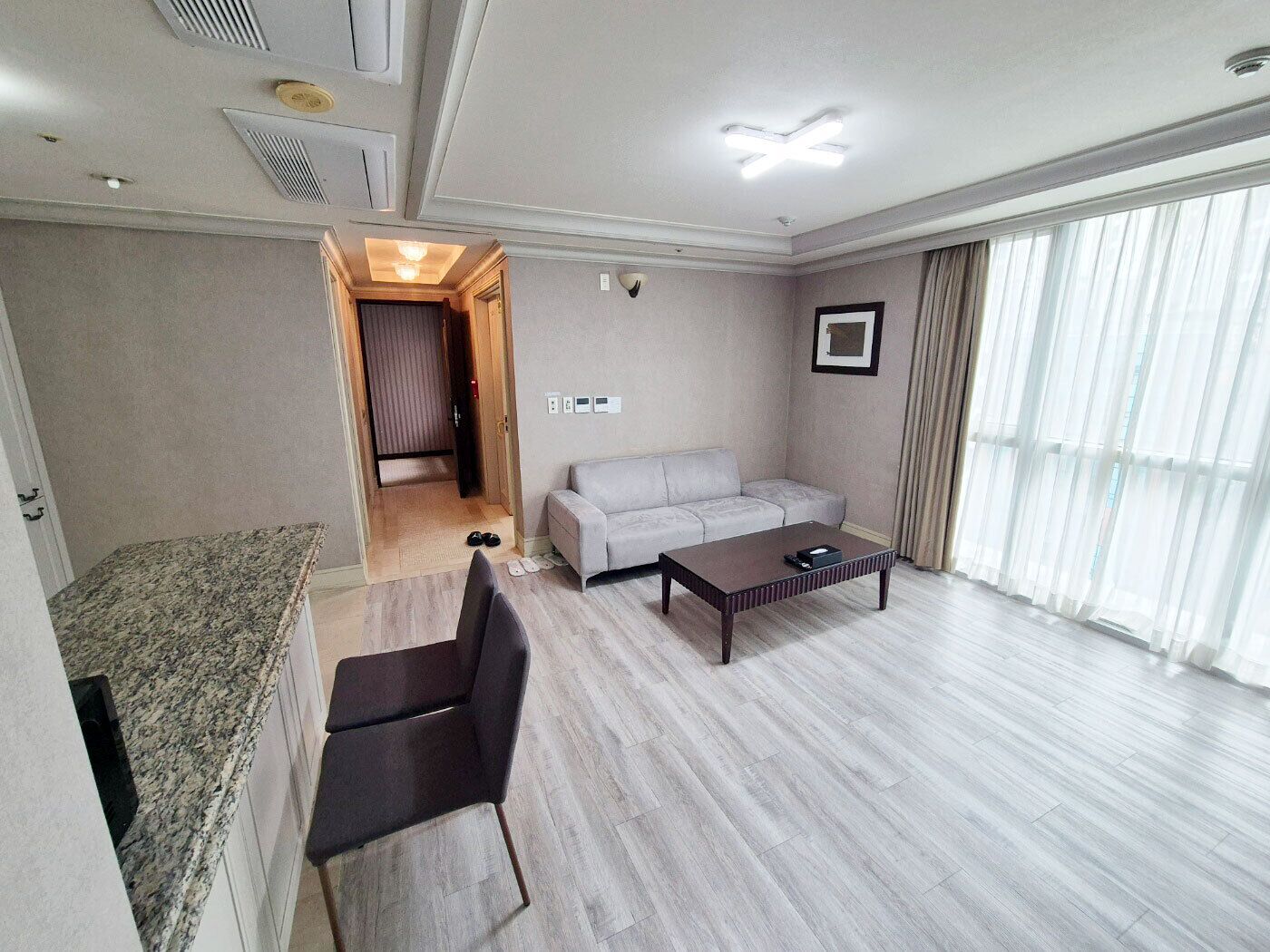 A modern living room with a sofa, coffee table, and a dining area with a granite countertop.