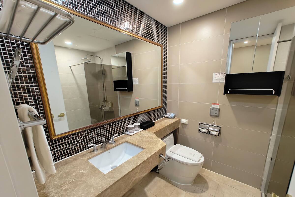 A modern bathroom with a sink, mirror, and toilet.