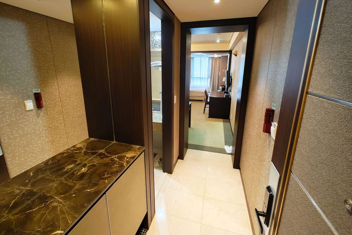 A hotel corridor with a marble counter, a bed, and a desk area.