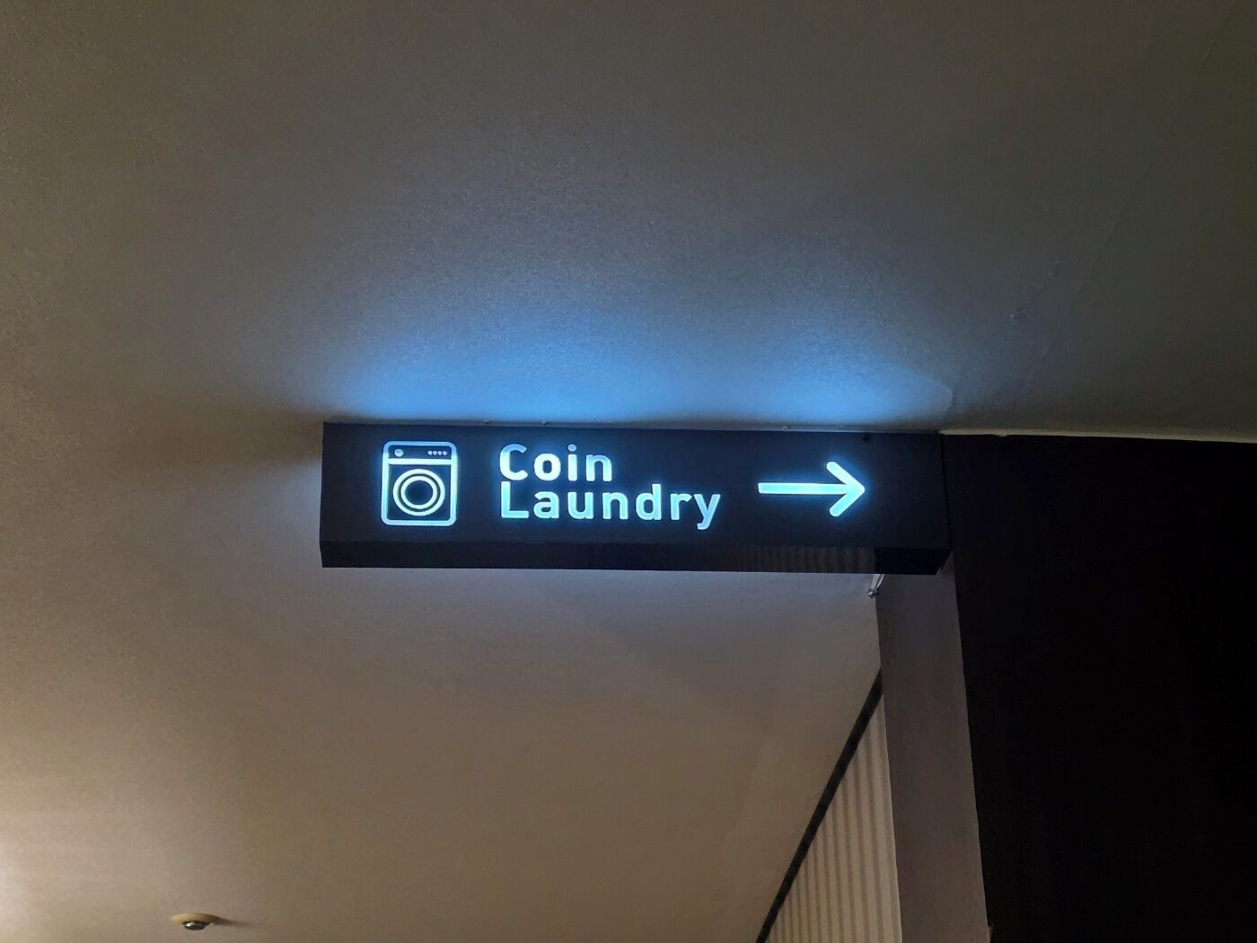 A neon sign for 'Coin Laundry' with an arrow pointing to the right.