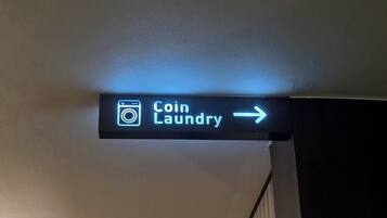 A neon sign for 'Coin Laundry' with an arrow pointing to the right.