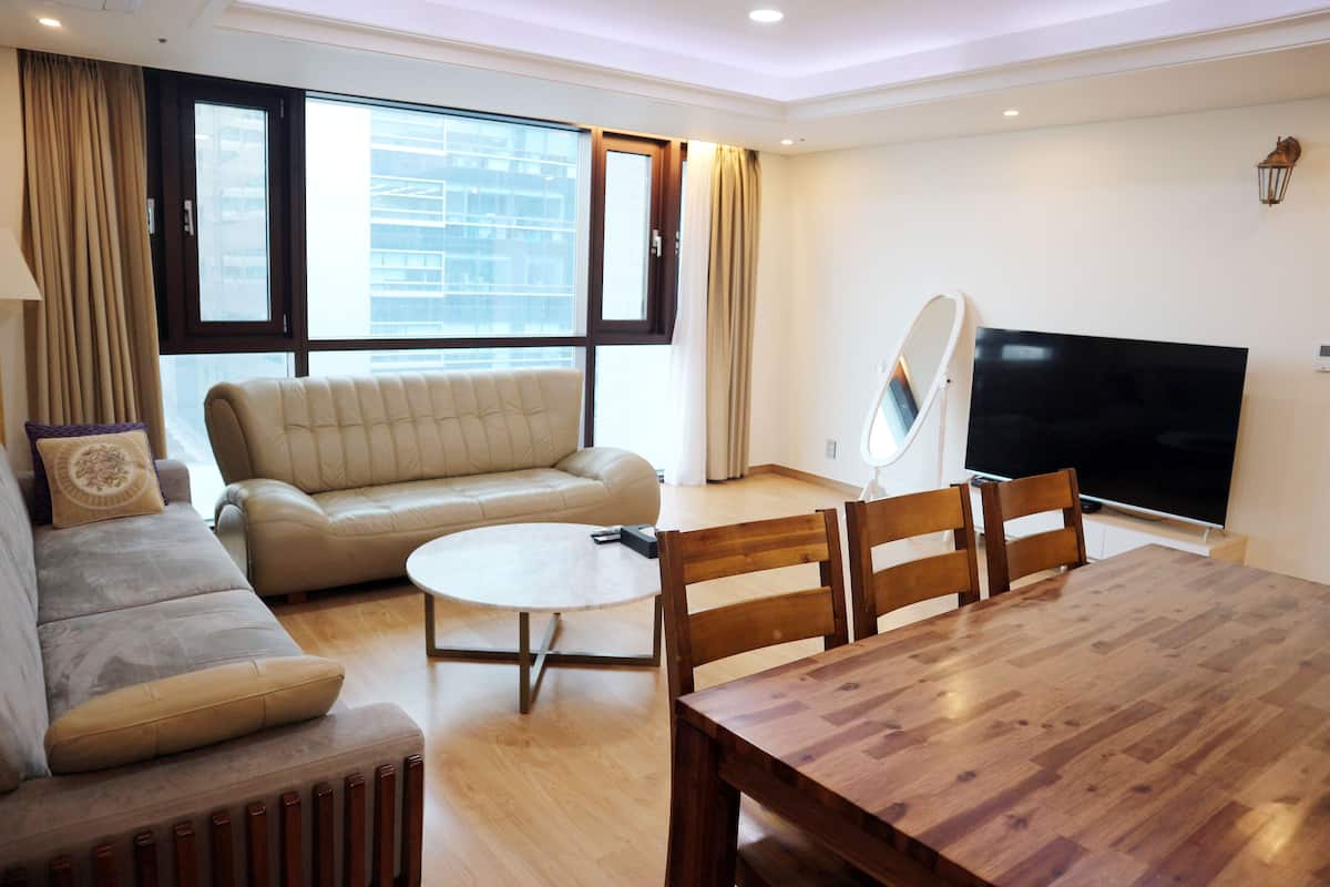 A modern living room with a sofa, a dining table, and a TV.