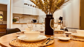 Une table à manger dressée avec de l’assiette blanche, des bols et des verres à vin, le tout entouré de sets de table en fibres tressées.
