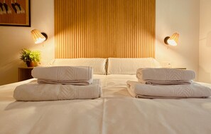 A hotel room with a bed, two bedside lamps, a potted plant, and folded towels. - Modern And Luxury Flat in Telde (Telde)