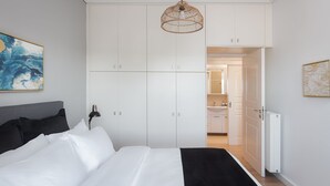 A bedroom with a bed, white wardrobe, and a hanging light fixture. - Glyfada Cozy Living (Glyfada)