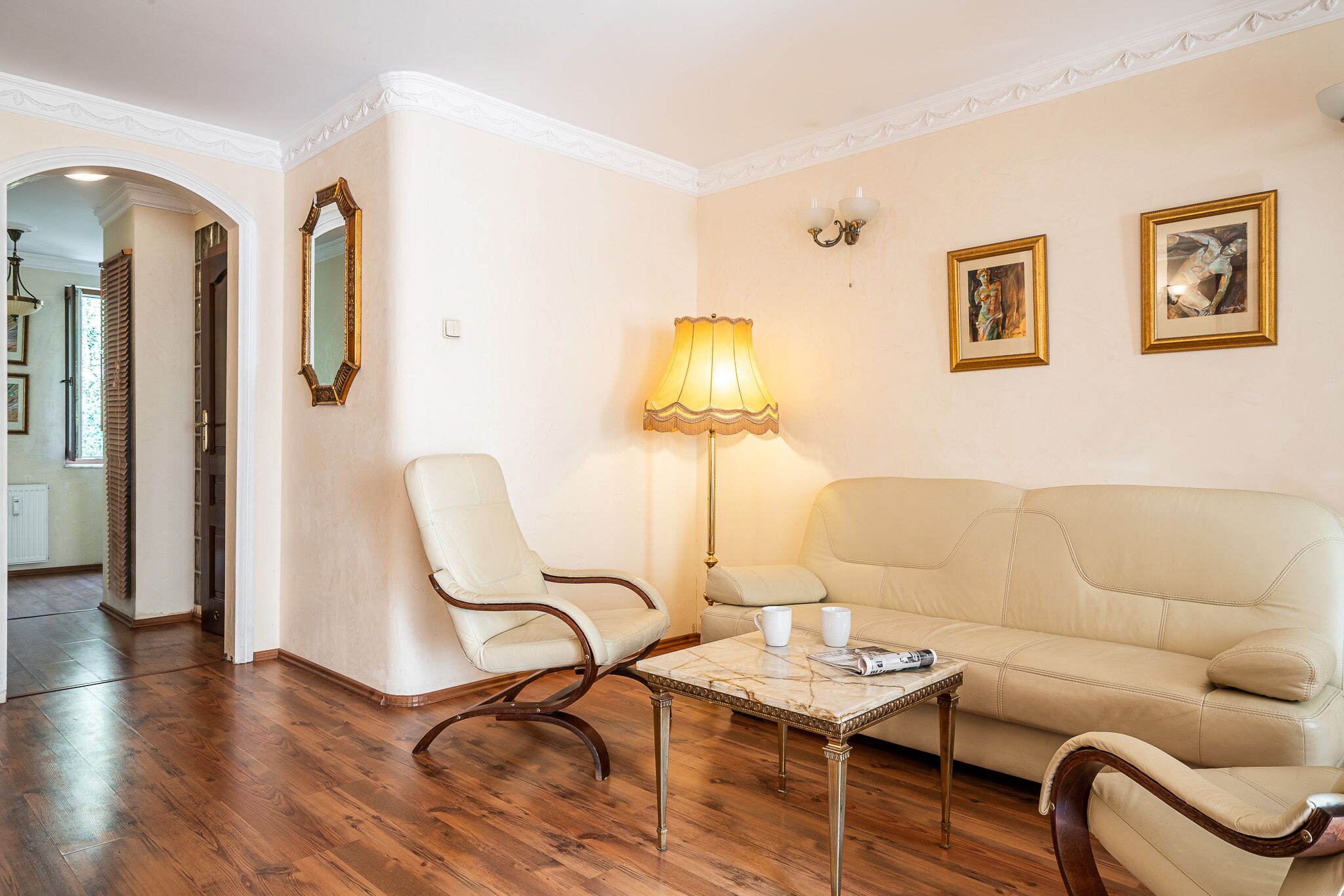 Ein Wohnzimmer mit einem beigen Sofa, einem passenden Sessel, einem Couchtisch und einer Stehlampe.
