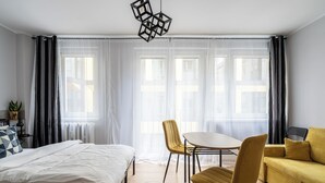 Une chambre d’hôtel moderne avec un lit, un canapé jaune, une table ronde et une chaise.