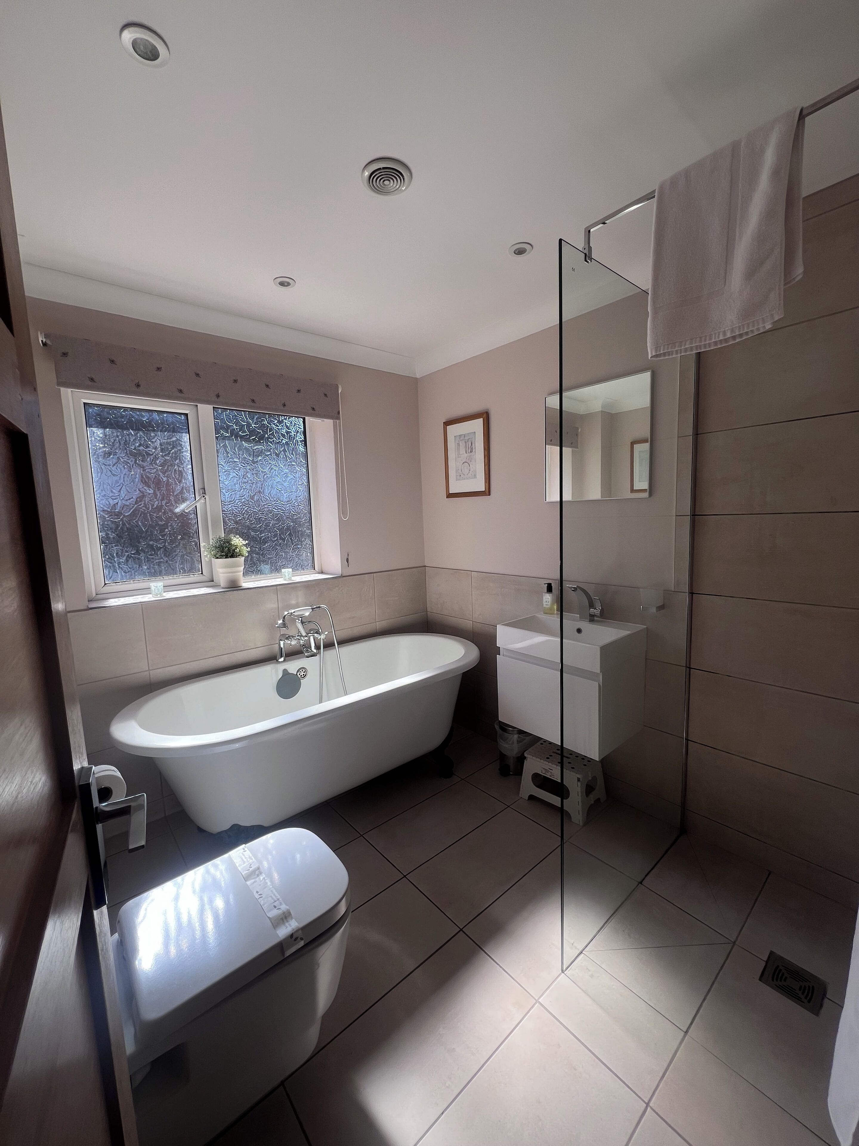 A modern bathroom with a freestanding bathtub, a glass-enclosed shower, and a white sink.