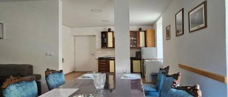 Amplia sala de estar con una larga mesa de comedor, sofás tapizados en azul y una cocina al fondo.