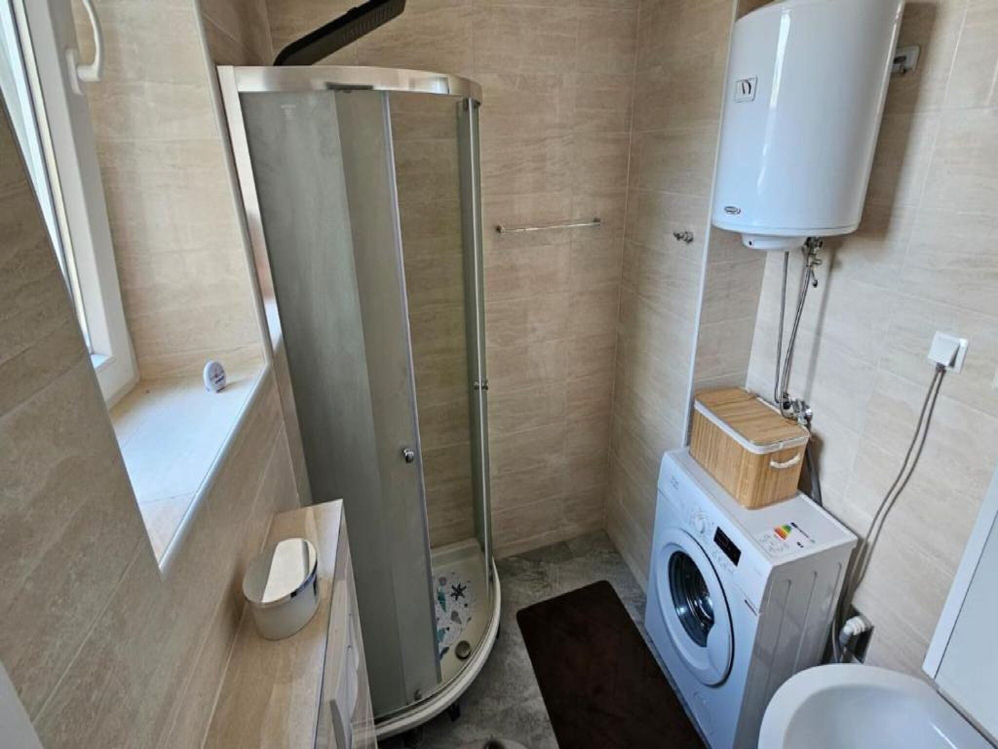 Un baño pequeño con cabina de ducha, lavadora e inodoro.
