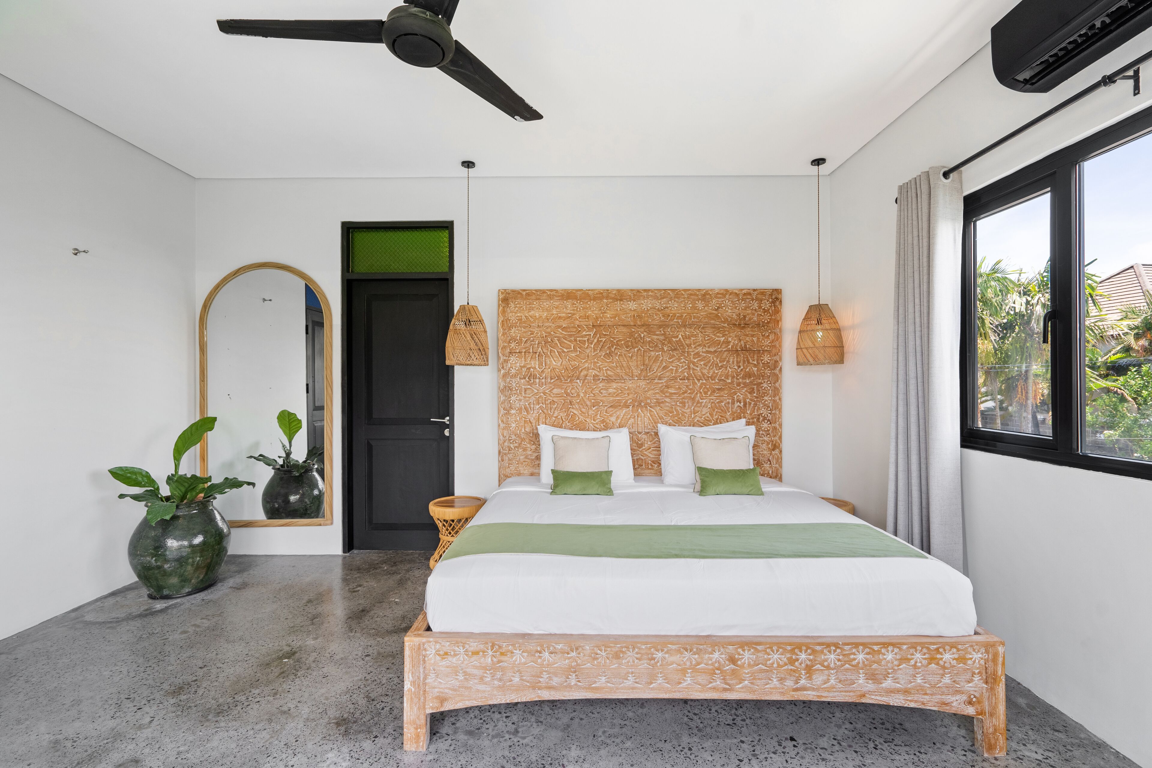 Un dormitorio con cama, ventilador de techo, ventana grande y espejo.