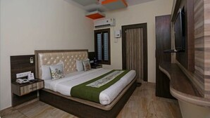 A hotel room with a large bed, a nightstand, a TV, and a curved wall. - Hotel Nagpal (Haridwar)