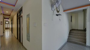 A hotel corridor with a carpeted floor, a staircase, and a ceiling with recessed lighting. - Hotel Nagpal (Haridwar)